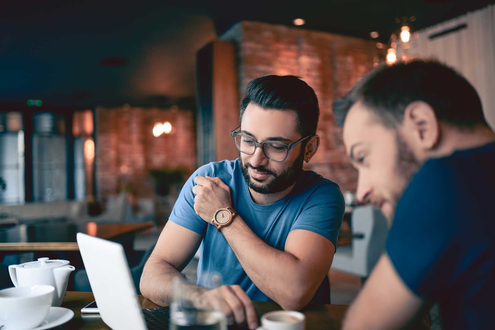 2 men reviewing the process of managing a full-time job and side business on a computer